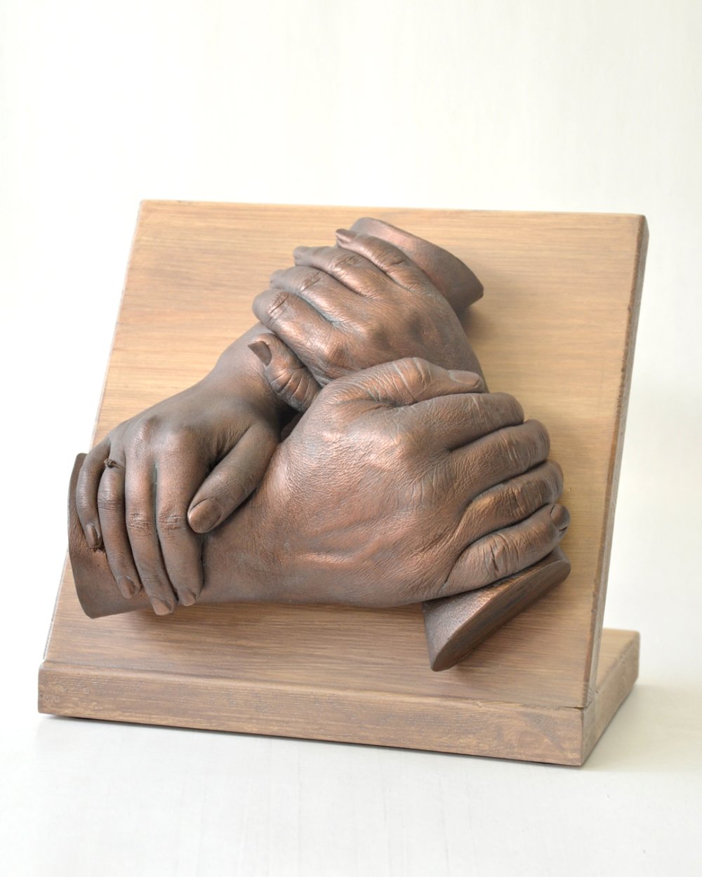Klassieke handenkrans van drie handen ineen, geplaatst op een paneel van steigerhout. Ideaal voor een plaatsing op een dressoir. Bodycasting in zijn klassieke vorm