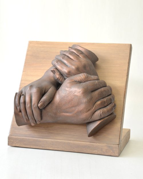 Klassieke handenkrans van drie handen ineen, geplaatst op een paneel van steigerhout. Ideaal voor een plaatsing op een dressoir. Bodycasting in zijn klassieke vorm