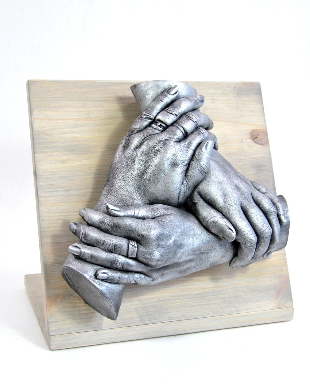 Klassieke handenkrans van drie handen ineen, geplaatst op een paneel van steigerhout. Ideaal voor een plaatsing op een dressoir. Bodycasting in zijn klassieke vorm