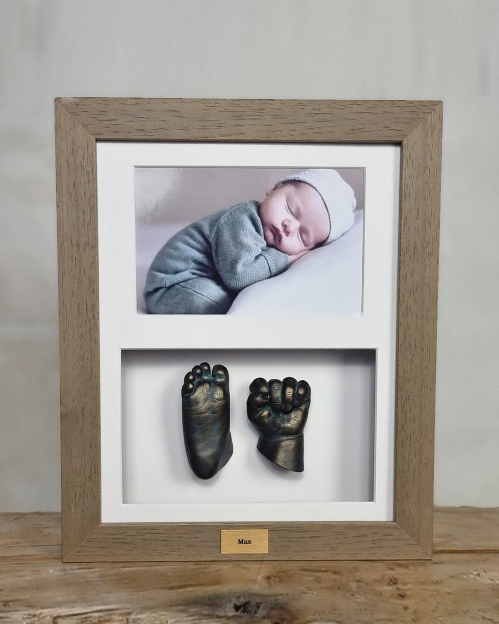 Een beeldje van het handje en voetje van een baby, geplaatst in een 3D lijst of schilderij, gemaakt door Bodycasting Nederland