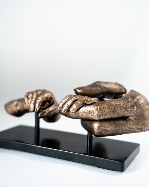 Bodycasting handbeeld van vader met handje van overleden kindje