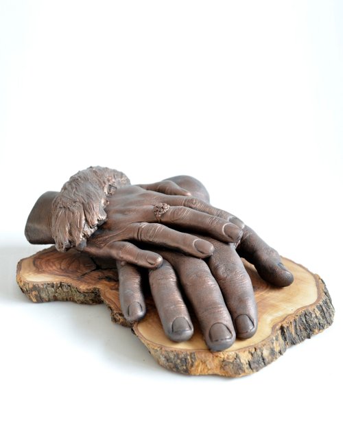 Bodycasting van hondenpoot op handen van baasje op olijfhouten basis