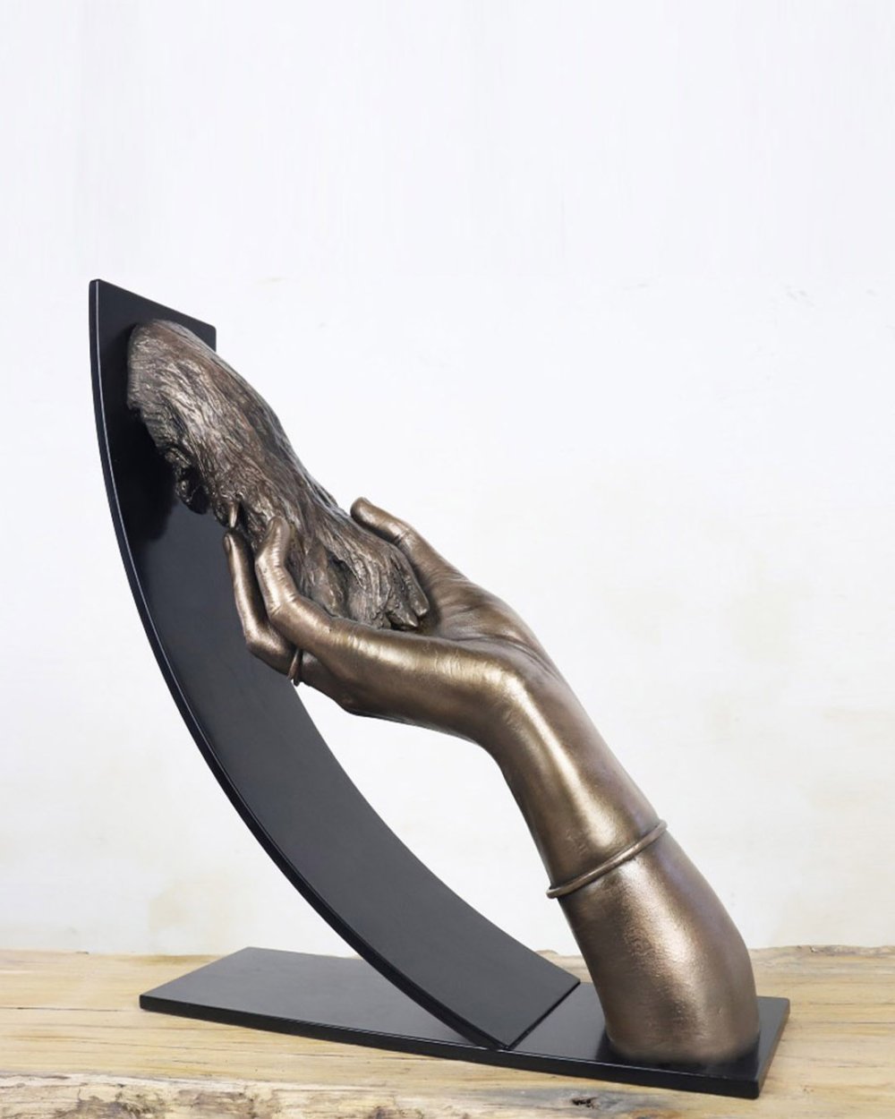 Bodycasting van hondenpoot en hand in gemetalliseerd kunstwerk met matzwarte metalen boogconstructie