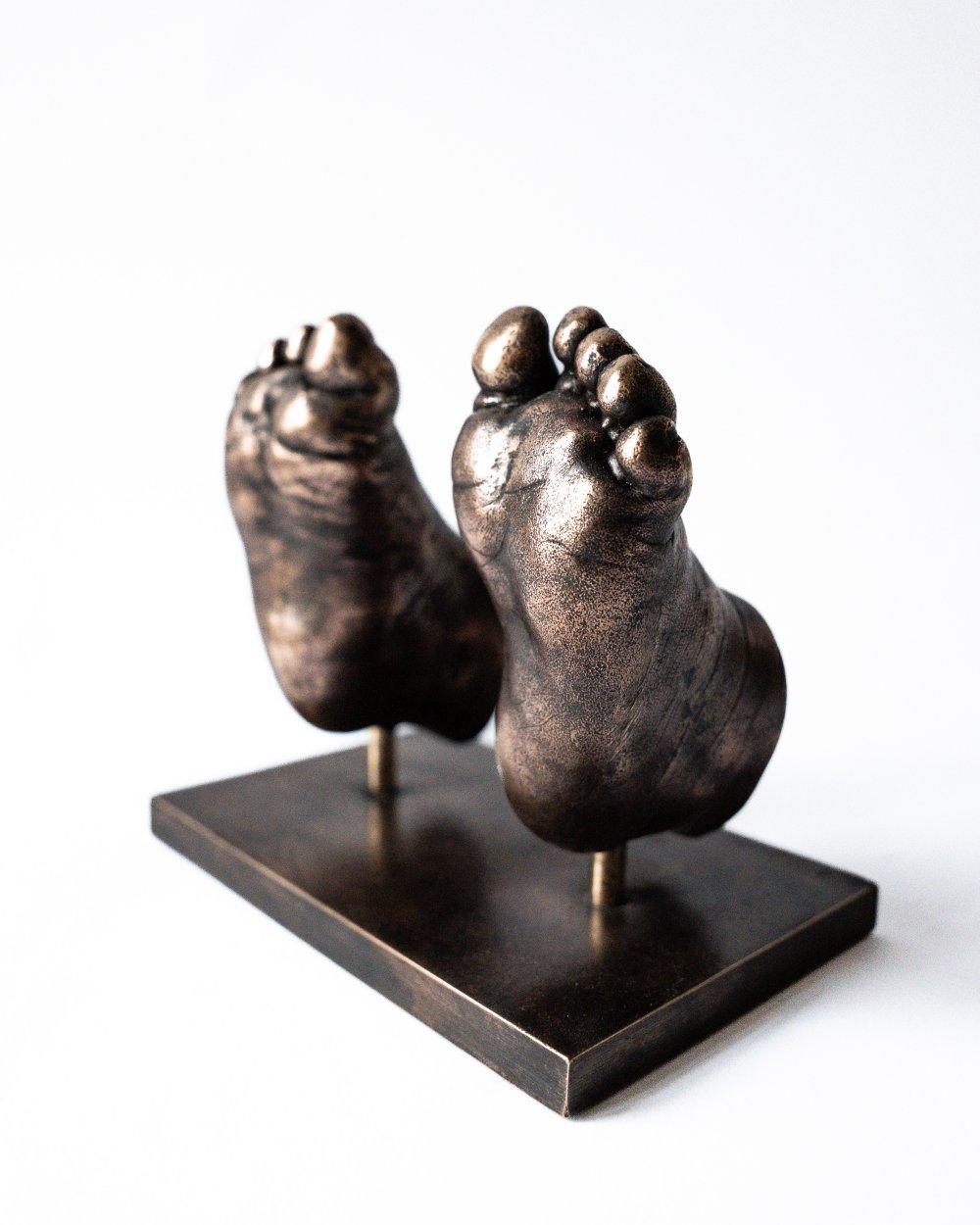 Bronzen babyvoetjes op metalen voetplaat gemaakt met bodycasting techniek
