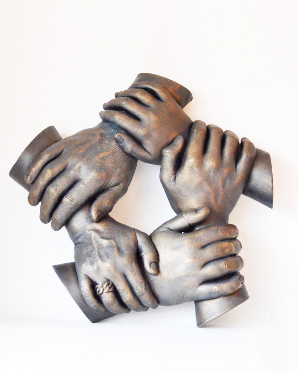 Een pure handenkrans, een krachtig beeld van vijf handen in ondoorbroken cirkel. Dit handbeeld in krans heeft een bronzen kleuring en bevat levensechte details.