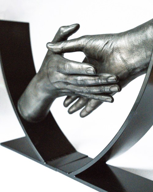 Handbeeld van twee handen die naar elkaar toe bewegen in metalen frame